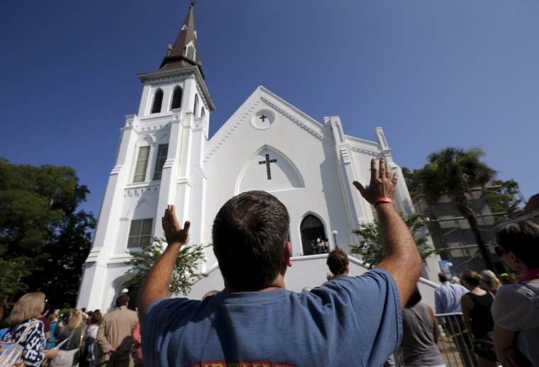 Image: Robin Goolfby raises his arms as church-goers who cannot fit into the Emanuel African Methodist Episcopal Church stand in the street during a service in Charleston