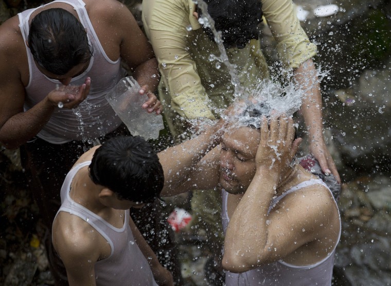 Image: Pakistanis cool themselves Tuesday under a broken water pipe in Islamabad as temperatures increase during Ramadan