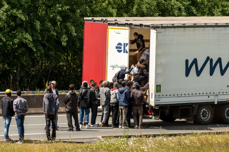 Image: Migrants climb in the back of a lorry on a highway leading to the Channel Tunne in Calais, northern France, Tuesday.