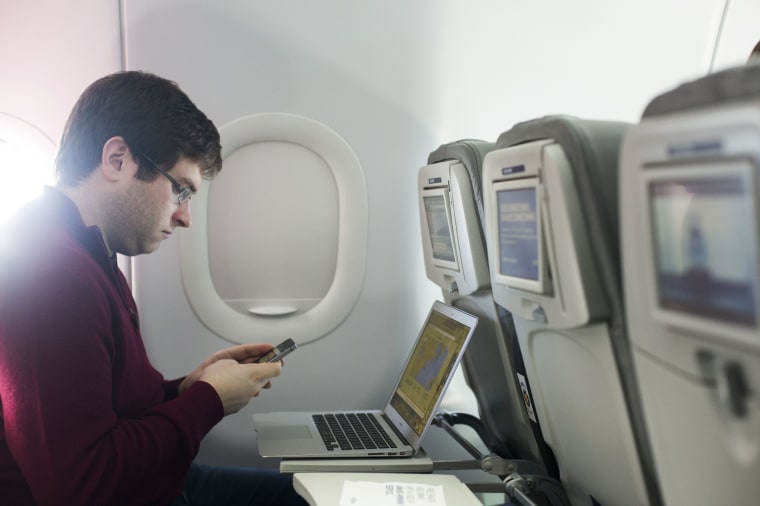 Image: A man uses his mobile phone and laptop to test a new high speed inflight Internet service named Fli-Fi while on a special JetBlue media flight out of John F. Kennedy International Airport in New York