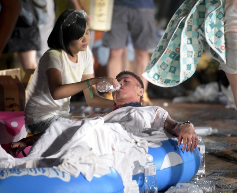 Image: A person helps an injured victim from an accidental explosion during a music concert at the Formosa Water Park in New Taipei City