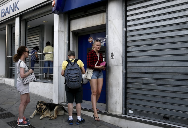 Image: People line up to withdraw cash from an ATM outside a Eurobank branch in Athens