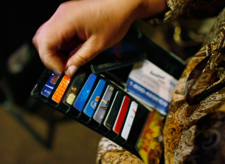 Image: A woman looks in her wallet for credit cards
