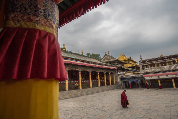 Image: A monk in a state of meditation with the famed Great Hall of the Gold Roof