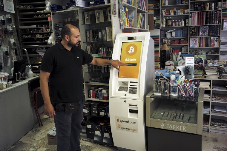 Image: A man demonstrates the use of a Bitcoin ATM at a bookstore in Acharnai in northern Athens, Greece