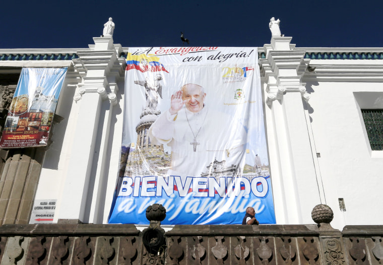 Image: A passerby walks by a banner of Pope Francis' upcoming visit to the country at the main square in Quito, Ecuador