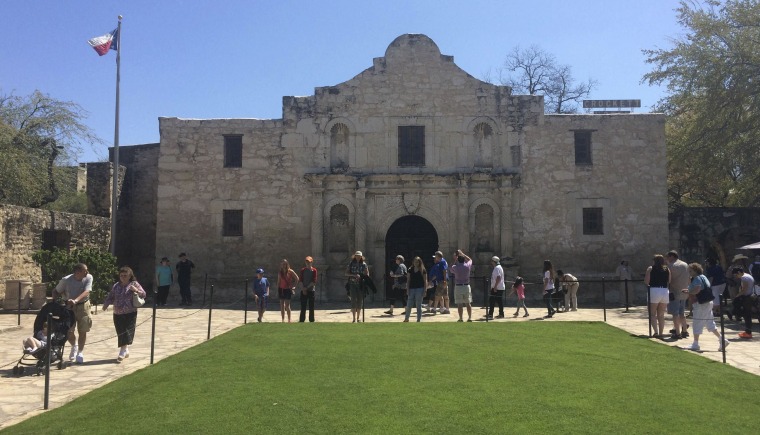 Image: Visitors walk at the entrance to the Alamo, the most-visited tourist site in the state, in San Antonio