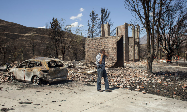 Image: Insurance claims adjuster surveys damage in the Broadview neighborhood where homes were consumed by the Sleepy Hollow fire in Wenatchee, Washington