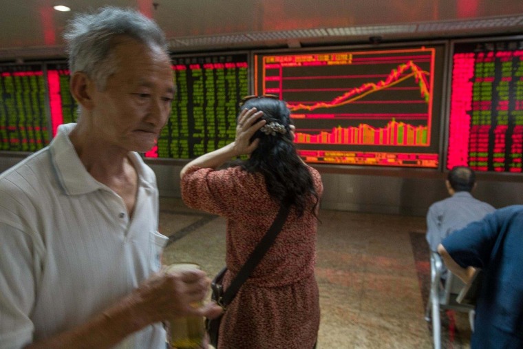 Image: Woman holds her head while watching stock price movements
