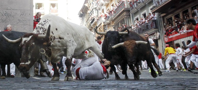 Image: A steer jumps over a fallen runner as two Jandilla fighting bulls follow behind at the Mercaderes curve during the first running of the bulls of the San Fermin festival in Pamplona