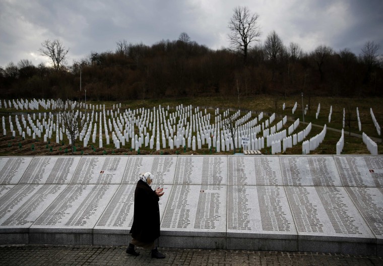 Image: Fadila Efendic prays near memorial plaques at the Potocari genocide memorial centre near Srebrenica