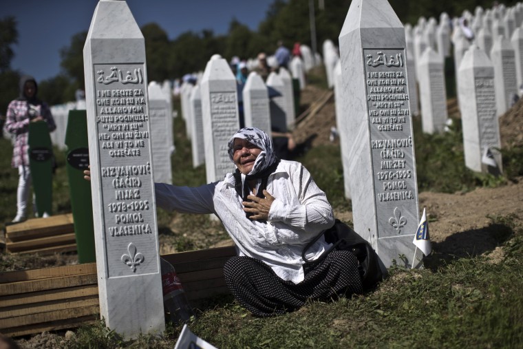 Image: A woman cries as she visits the grave of a family member at the Potocari memorial complex