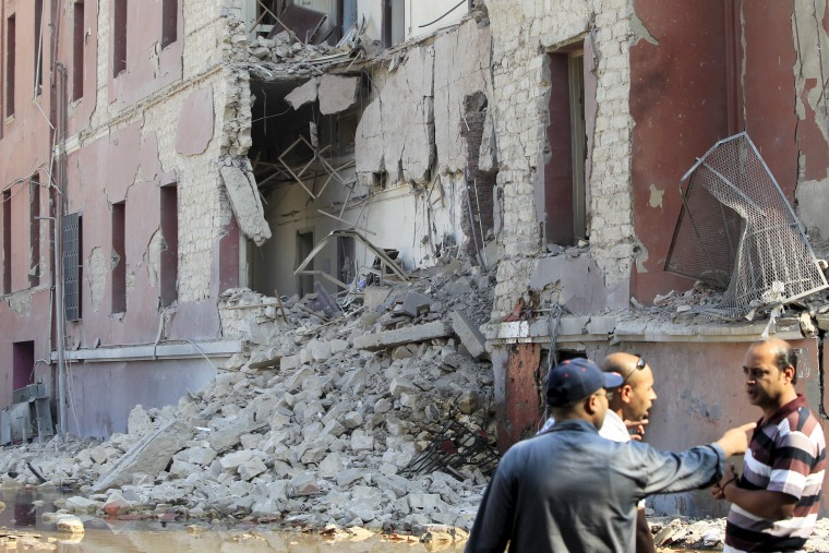 Image: Onlookers stand near the site of a bomb blast at the Italian Consulate in Cairo