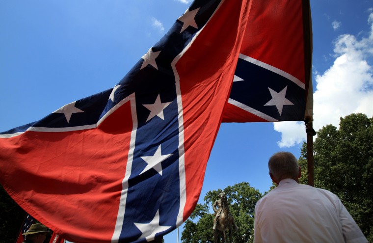Image: Eddie Miller holds a Confederate flag in front of the statue and tomb of Nathan Bedford Forrest