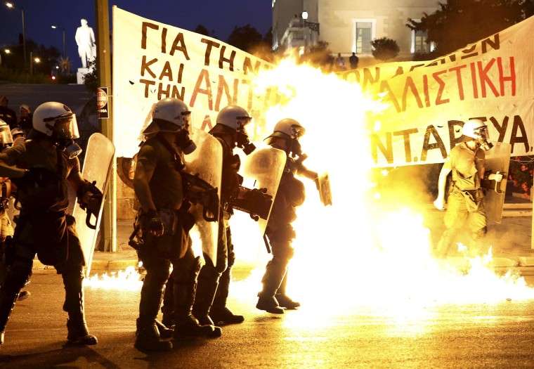 Image: Riot police stand amongst flames from petrol bombs thrown by a small group of anti-establishment demonstrators in Athens