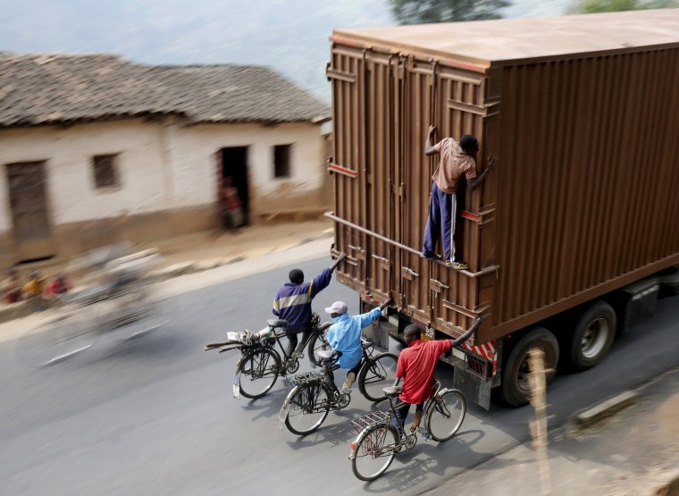 Image: Cylists hang to the back of a truck outside the capital Bujumbura as the country awaits next week's presidential elections