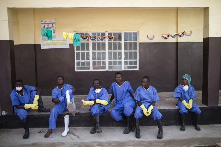 Image: Health workers rest outside a quarantine zone at a Red Cross facility in the town of Koidu