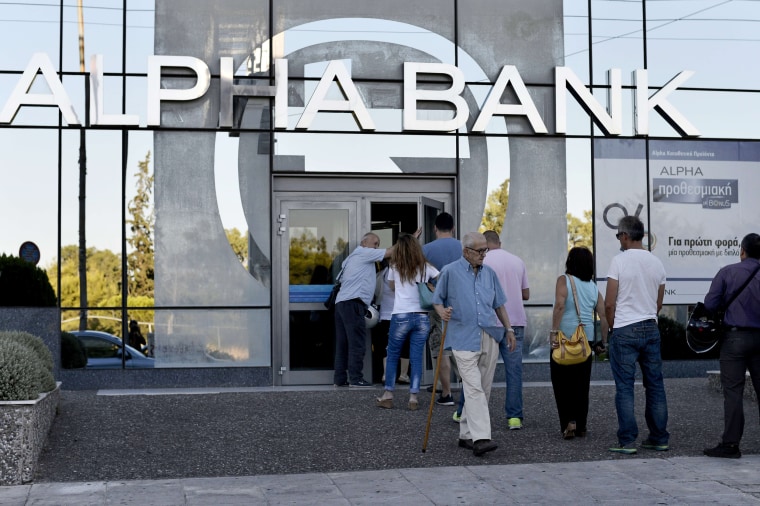 Image: Customers wait to enter a bank in Athens