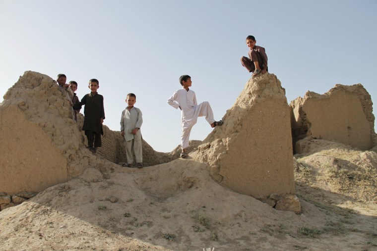 Image: Afghan boys play on ruins of a house