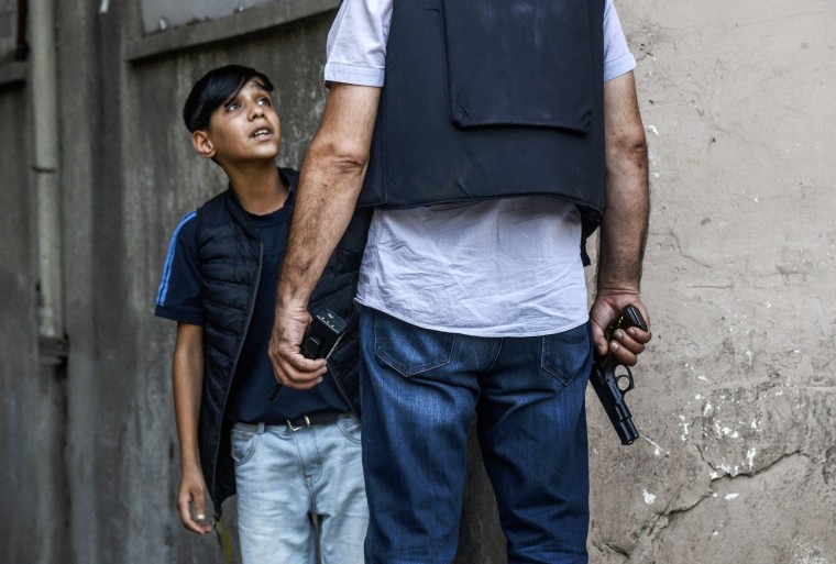 Image: A Turkish police officer asks questions to a young Kurdish boy after an attack against police officers in the center of Diyarbakir, Thursday.