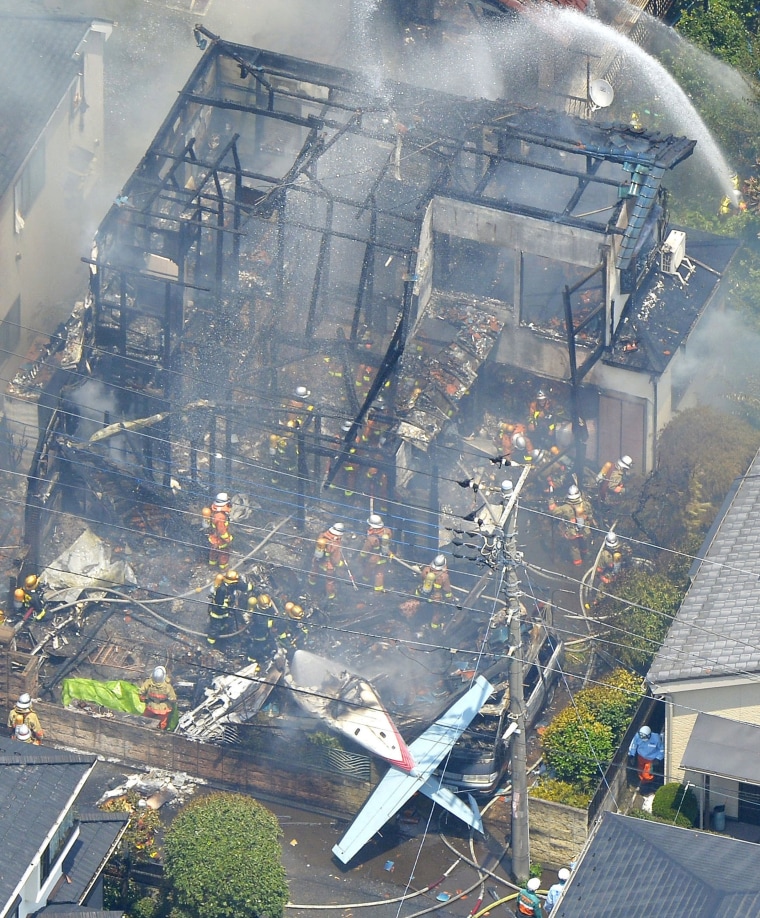 Image: An aerial view shows debris of a crashed light plane and burning houses are seen after the plane went down in a residential area and burst into flames, in Chofu, outskirt of Tokyo