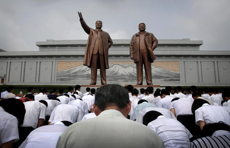 Image: North Koreans bow in front of bronze statues of the late leaders Kim Il Sung and Kim Jong Il