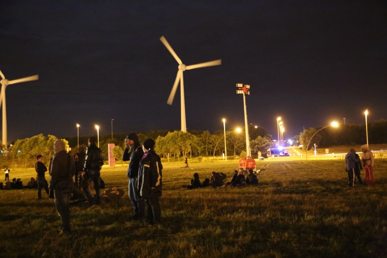 Image: Migrants sleep and eat  outside of a supermarket in Calais, France