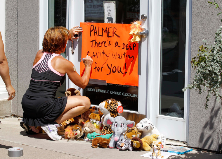 Image: A woman writes on a sign outside Dr. Walter James Palmer's dental office