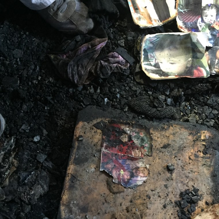 Image: Burned family pictures sit on the ground of a home in Duma, West Bank