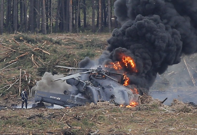 Image: A pilot stands near a burning Mi-28N helicopter after a hard touchdown during the "Aviadarts" military aviation competition near Ryazan