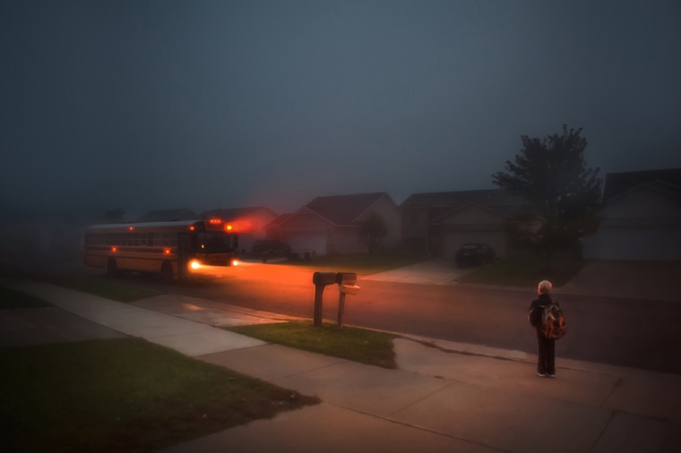Boy waiting for school bus in the dark