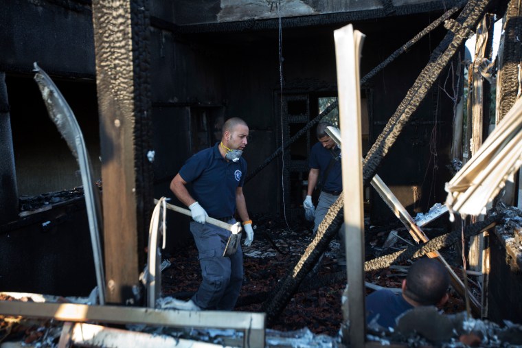 Image: Israeli police officers inspect a torched house in Duma, West Bank