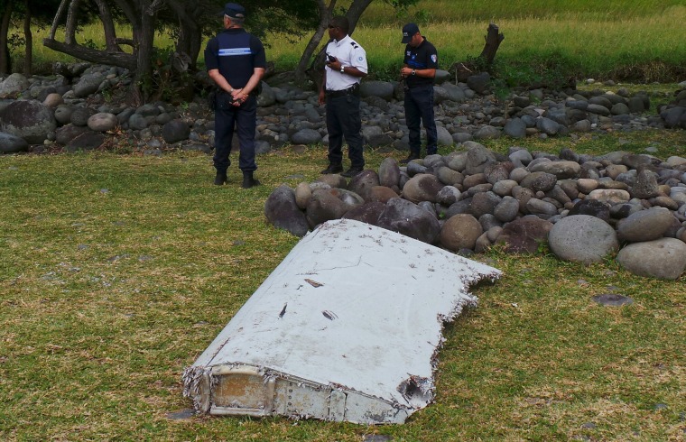 Image: Officials stand near plane debris which was found on Reunion Island