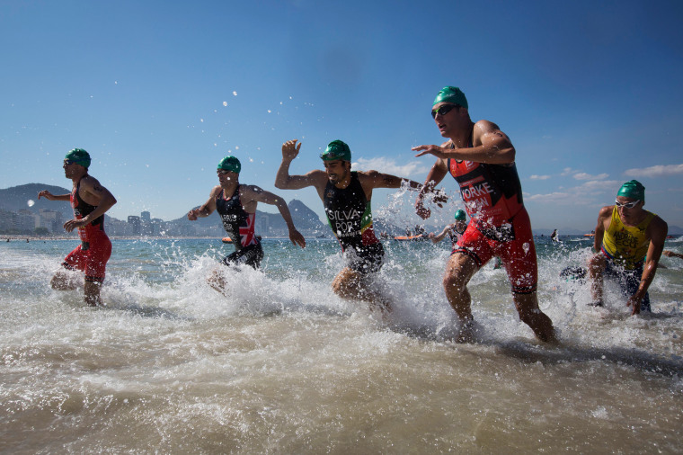 Image: Triathletes exit the water during the men's triathlon