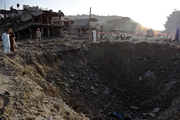 Image: Afghan security forces and residents stand near the crater from a powerful truck bomb in Kabul