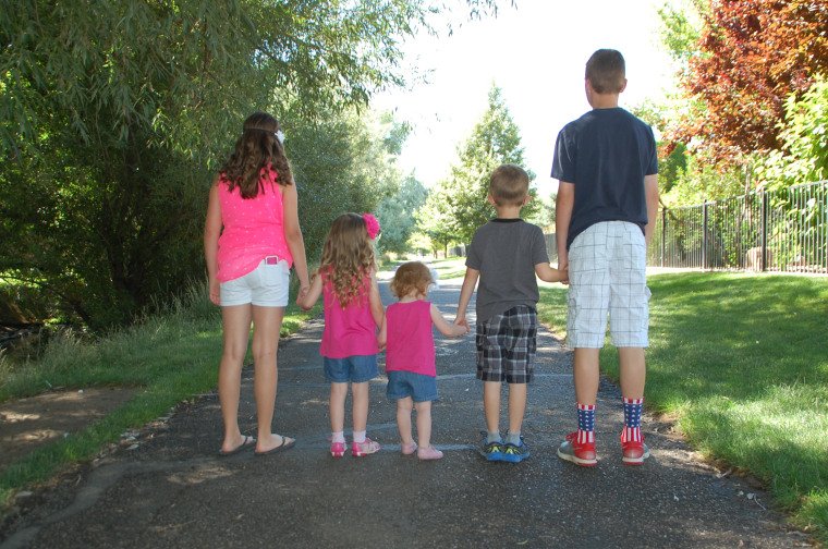 Elementary-aged kids standing with backs toward camera