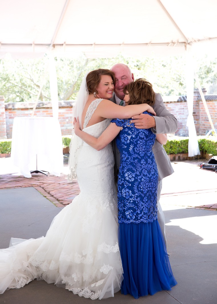 Family hugging daughter on her wedding day