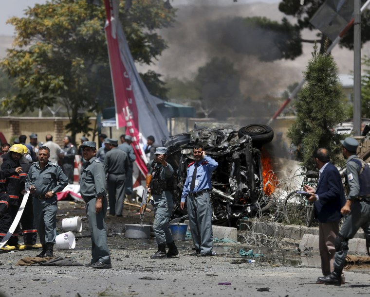Image: Police stand at the site of a car bomb blast at the entrance gate to the Kabul airport