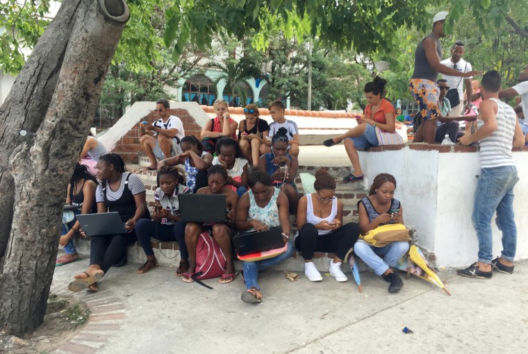 Image:  A group of people congregate around lunchtime in the Villa Panamericana neighborhood near Cojimar try to connect at a new Wifi hotspot, though service is sporadic and expensive.