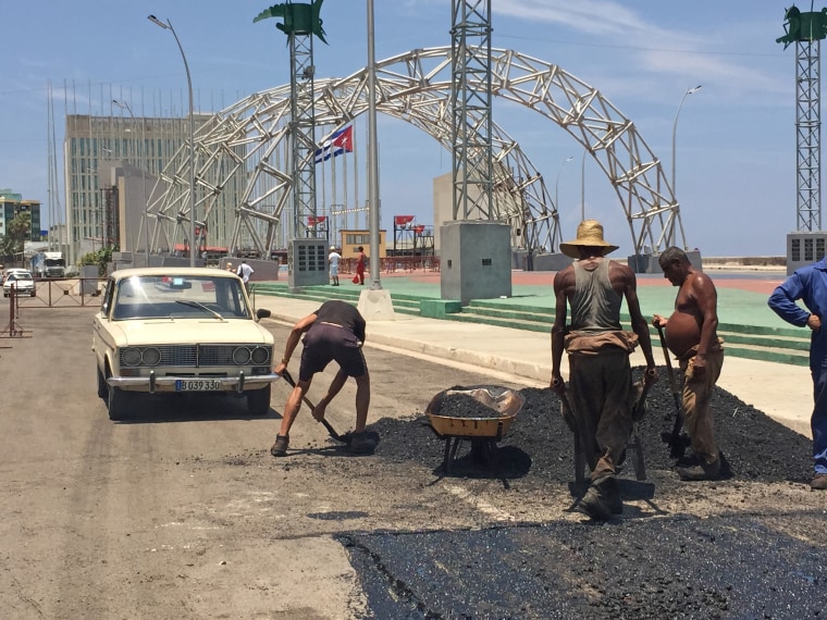 Workers pour asphalt to cover potholes along the Malecon on Aug. 12 in preparation for the flag-raising ceremony at the U.S. Embassy.