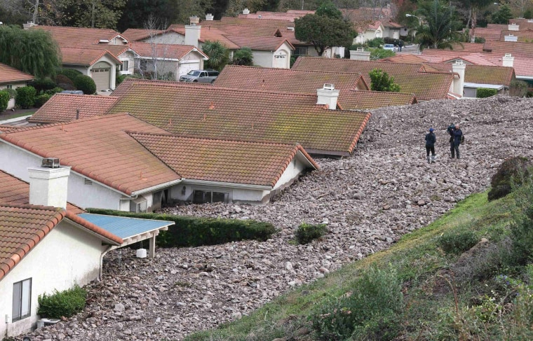 Image: A TV news crew files a report behind damaged homes after a mud slide in Camarillo Springs, California