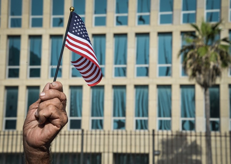 Image: A Cuban holds a little US flag in front of the US Embassy in Havana