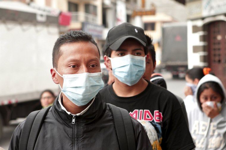 Image: People wear surgical masks to protect themselves from volcanic ash in Machachi