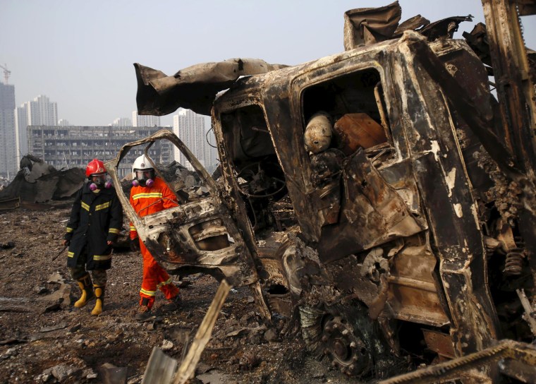 Image: Firefighters walk past a damaged truck at the site of Wednesday night's explosions in Binhai new district of Tianjin