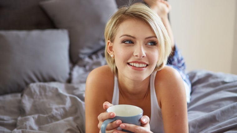 Woman drinks coffee in bed