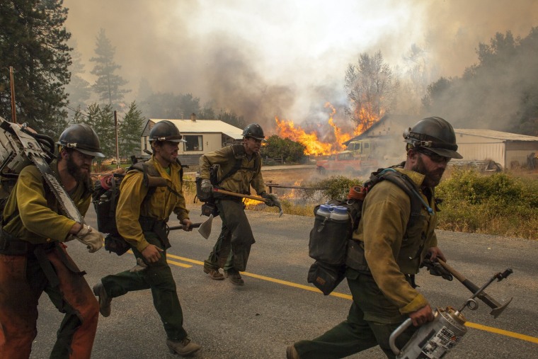 Image: Firefighters flee as the Twisp River fire advanced unexpectedly on Thursday