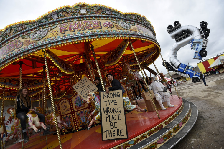 Image: People ride a carousel at 'Dismaland'