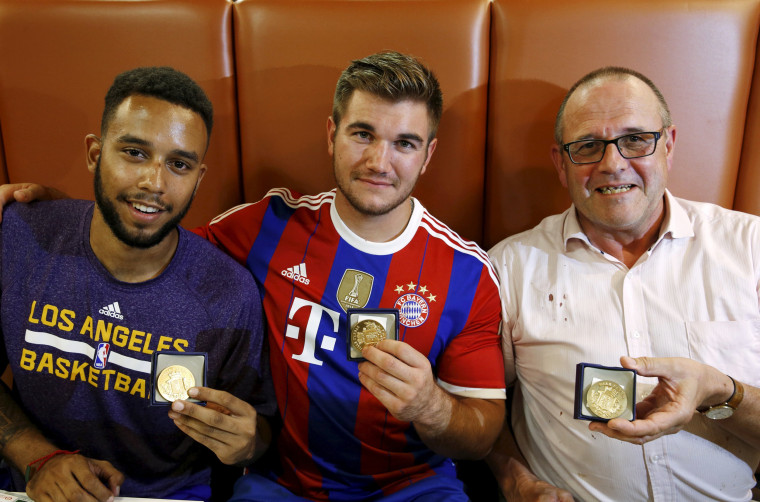 Image: Sadler, Sharlatos, and Norman, three men who helped to disarm an attacker on a train from Amsterdam to France, pose with their medals at a restaurant in Arras, France
