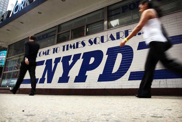 Image: People walk by an NYPD outpost in Times Square