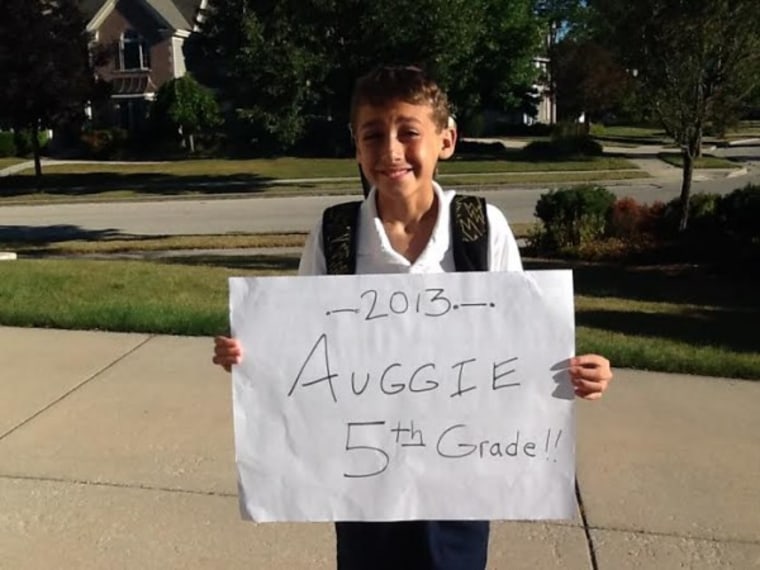 Boy holding fifth-grade sign